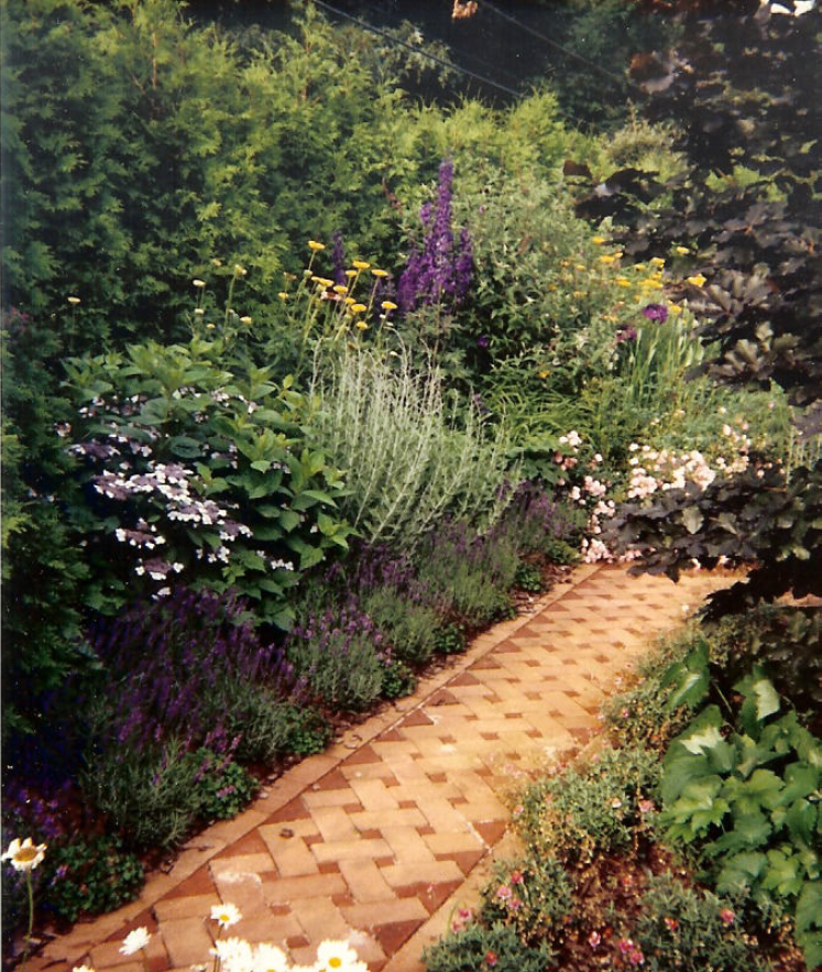 The Maria Garden — hydrangeas, roses, and lavender along a checkerboard brick path.
