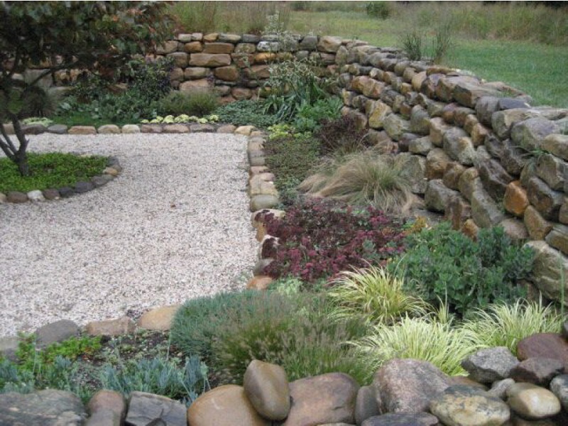 Native fieldstone wall enclosing a sunken garden that doubles as natural drainage.